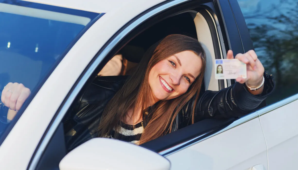 A woman proudly showing her drivers license after regaining her driving privileges