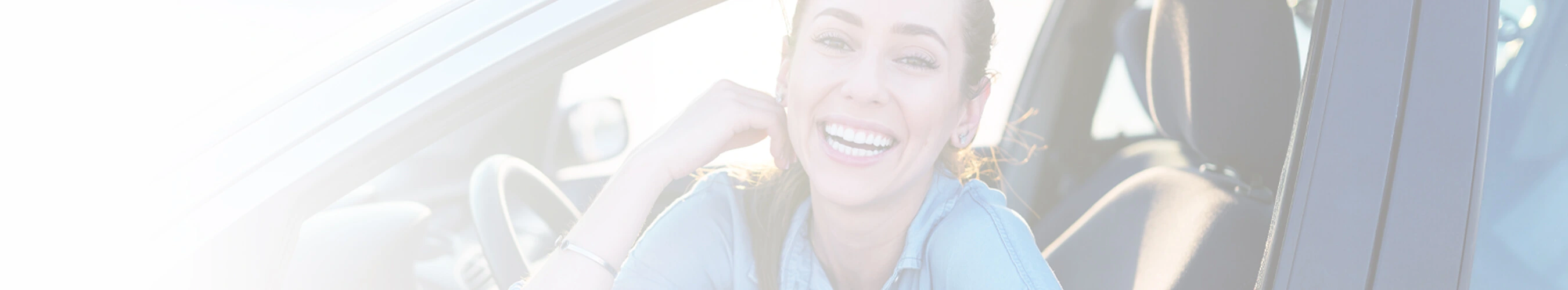 Smiling woman leaning on a car window with sunlight filtering in