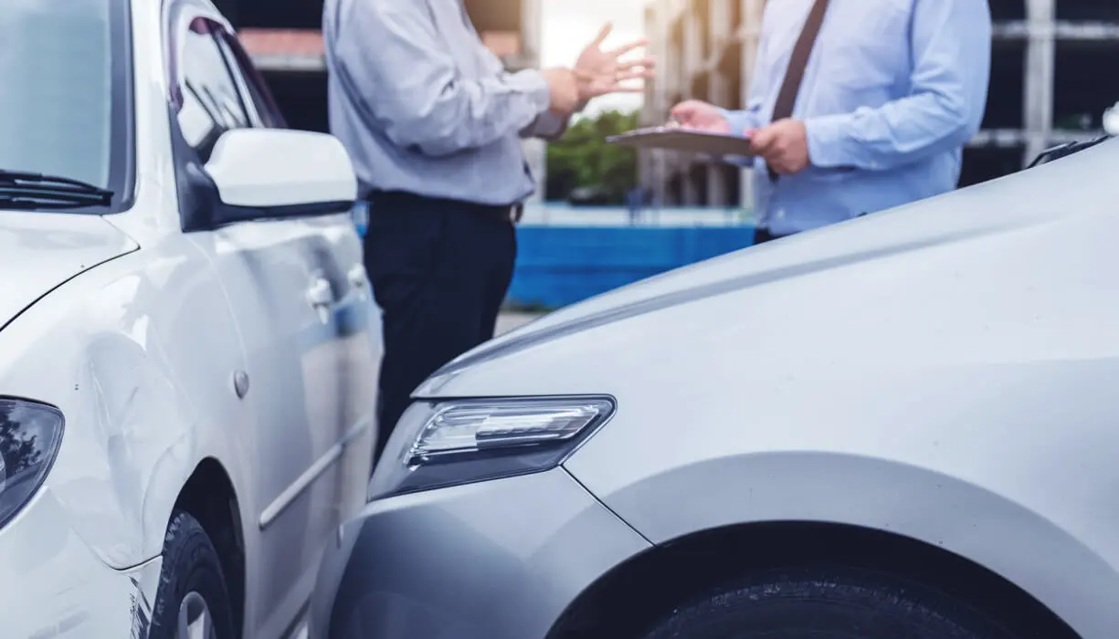 Insurance Agent with customer examine the damage to two cars involved in a minor collision.